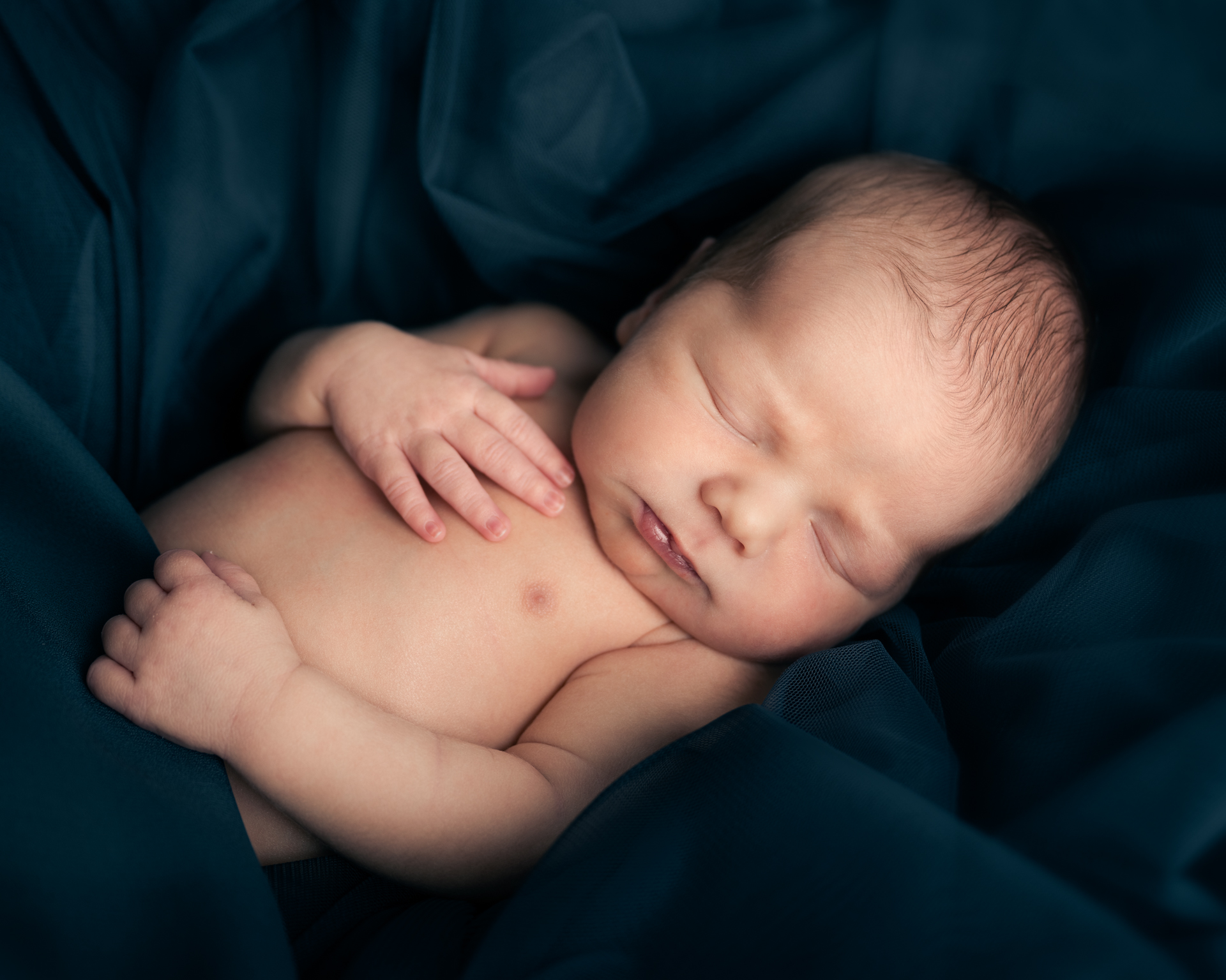 en liten gutt som sover under nyfødtfotograferingen.