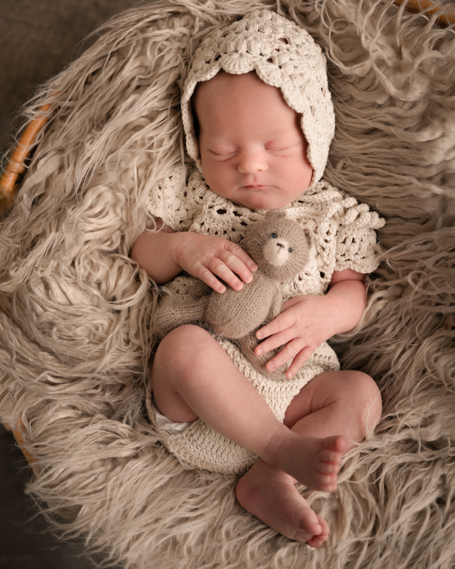 sovende baby med bamse i hånden fotografert med jordfarger